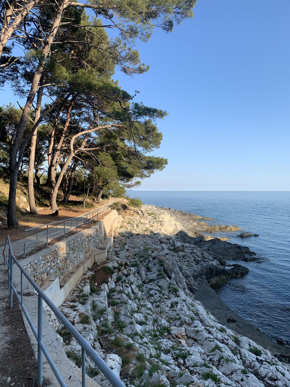 Pobrežná promenáda v tieni borovíc v zátoke Čikat